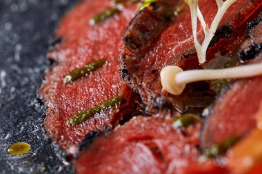 Biftek carpaccio soslu ve domatesli siyah masa. Restoran menüsü, doğal ve organik gıda konsepti..