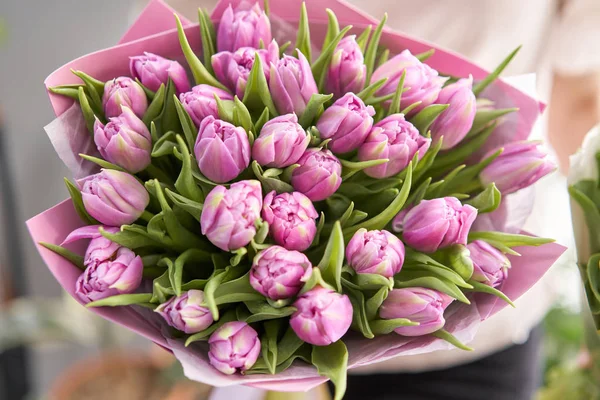 Junge schöne Frau mit einem Frühlingsstrauß aus gelben Tulpen in der Hand. Bund frisch geschnittener Frühlingsblumen in weiblichen Händen — Stockfoto