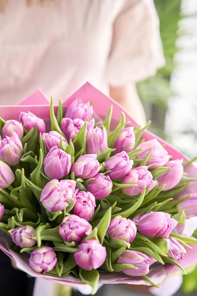 Young beautiful woman holding a spring bouquet of yellow tulips in her hand. Bunch of fresh cut spring flowers in female hands — Stock Photo, Image