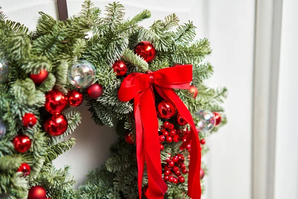 Linda grinalda de Natal vermelho de abeto fresco na porta branca. Entrada para a casa. Humor de Natal. Árvore natal . — Fotografia de Stock