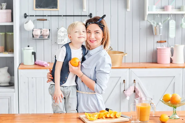 Mother and son are smiling while having a breakfast in kitchen. Bright morning in the kitchen. Healthy Breakfast cereals and fresh fruit.