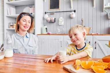 Anne ve oğul mutfakta bir kahvaltı yaparken gülümsüyorsun. Anne süt cam içine yağıyor