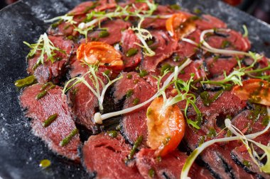 Biftek carpaccio soslu ve domatesli siyah masa. Restoran menüsü, doğal ve organik gıda konsepti..