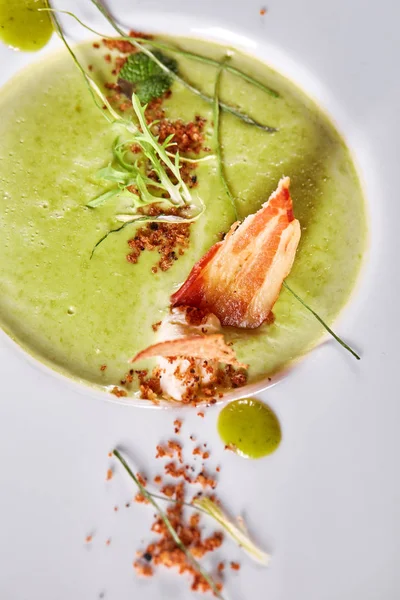 Crema vegetale minestra di piselli verdi in un piatto bianco. Minestra di purea con cracker e pancetta affumicata . — Foto Stock