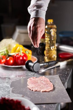 Şef domuz pirzolası ve terbiye eder. Restoran mutfağında profesyonel bir aşçı..