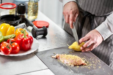 Şef tavuk doğrayıp terbiye ediyor. Restoran mutfağında profesyonel bir aşçı..