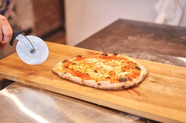 İtalyan mutfağı ve yemek pişirme konsepti. Napoli Pizzacısı 'nda pizza dilimleyen bir şef..