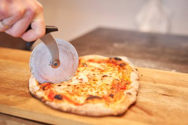 İtalyan mutfağı ve yemek pişirme konsepti. Napoli Pizzacısı 'nda pizza dilimleyen bir şef..