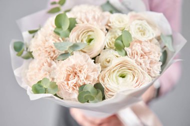 Kadınların elinde İranlı düğün çiçeği. Yeşil okaliptüslü soluk pembe ranunculus çiçekleri. Çiçekçi dükkanındaki çiçekçinin işi.