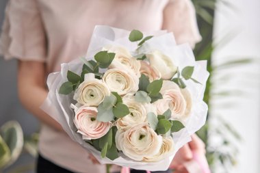 Kadınların elinde İranlı düğün çiçeği. Yeşil okaliptüslü soluk pembe ranunculus çiçekleri. Çiçekçi dükkanındaki çiçekçinin işi.