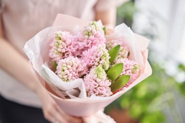 Genç, mutlu bir kadın elinde pembe sümbüller tutuyor. Gülümseyen bir kıza hediye. Çiçek buketi.