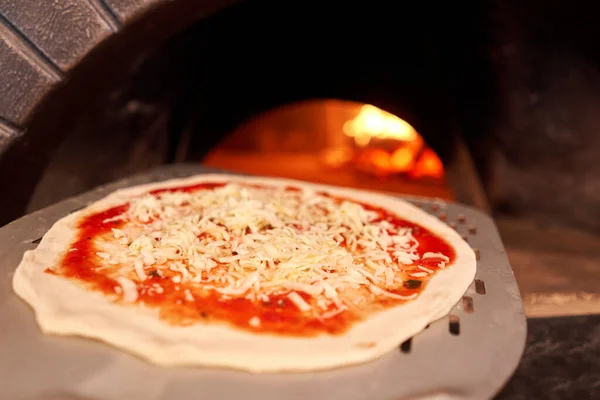 Billetta cruda per la cottura della gustosa pizza margherita nel forno tradizionale a legna nel ristorante napoletano. Pizza napoletana originale. Carbone caldo rosso . — Foto Stock