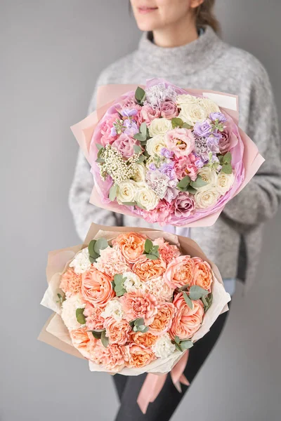Dos hermosos ramos de flores mixtas en manos de mujeres. el trabajo de la floristería en una florería. Entrega flor cortada fresca. Tienda floral europea . — Foto de Stock