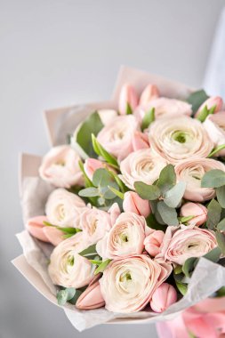 Soluk pembe laleler ve yeşil okaliptüslü ranunculus çiçekleri. Çiçekçi dükkanındaki çiçekçinin işi..