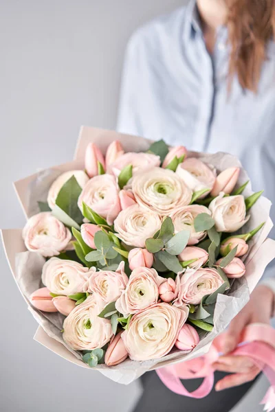 Букет з блідо-рожевих тюльпанів і квітів рунункули з зеленим евкаліптом. Робота флориста в квітковому магазині . — стокове фото
