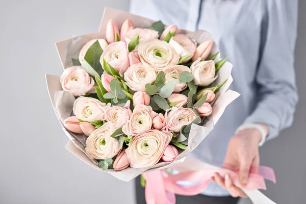 Букет з блідо-рожевих тюльпанів і квітів рунункули з зеленим евкаліптом. Робота флориста в квітковому магазині . — стокове фото