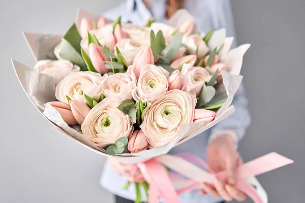 Ramo de tulipanes rosados pálidos y flores de ranúnculo con eucalipto verde. El trabajo de la floristería en una floristería . — Foto de Stock