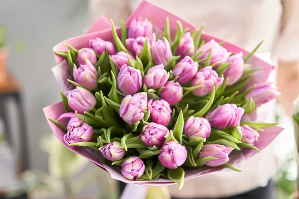 Jeune belle femme tenant dans sa main un bouquet printanier de tulipes jaunes. Bouquet de fleurs printanières fraîches coupées dans les mains des femmes — Photo