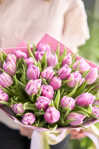 Junge schöne Frau mit einem Frühlingsstrauß aus gelben Tulpen in der Hand. Bund frisch geschnittener Frühlingsblumen in weiblichen Händen — Stockfoto