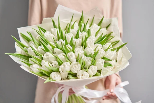 Молодая красивая женщина с весенним букетом белых тюльпанов в руке. Куча свежих срезанных весенних цветов в женских руках — стоковое фото