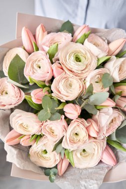 Soluk pembe laleler ve yeşil okaliptüslü ranunculus çiçekleri. Çiçekçi dükkanındaki çiçekçinin işi..