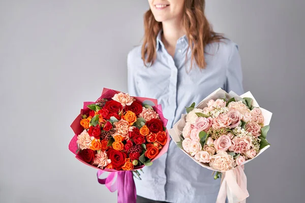 Dos hermosos ramos de flores mixtas en manos de mujeres. el trabajo de la floristería en una florería. Entrega flor cortada fresca. Tienda floral europea . — Foto de Stock