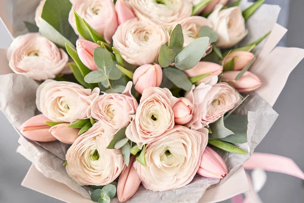 Ein Bündel blassrosa Tulpen und Hahnenfußblüten mit grünem Eukalyptus. Die Arbeit des Floristen im Blumenladen. — Stockfoto