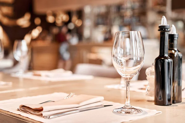 Copas de vino en primer plano. Las sillas y la mesa para los huéspedes, servidas con cubiertos y vajilla —  Fotos de Stock