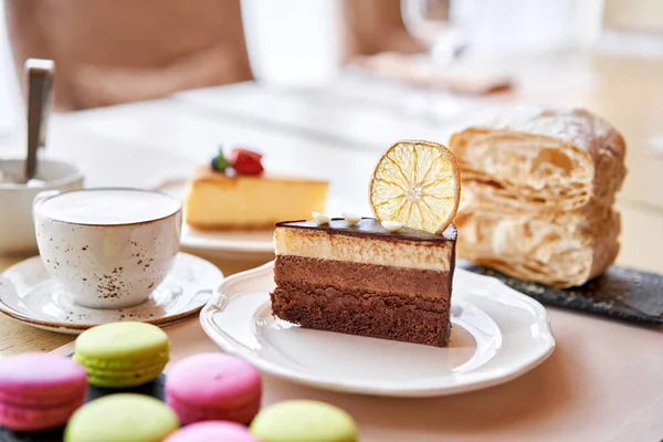 Шоколадный бисквит, с муссом, украшенный апельсиновым ломтиком и безе. Завтрак в кафе, утренний кофе. на деревянном столе . — стоковое фото
