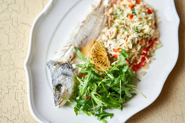 Grillowany okoń morski. Sałatka i ryż ze świeżymi warzywami. Serwując na białym talerzu na drewnianym stole. Menu restauracji. — Zdjęcie stockowe