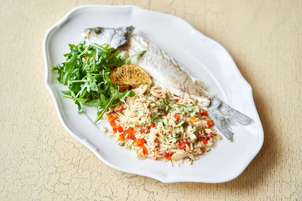 Grillezett tengeri sügér. Saláta és rizs friss zöldségekkel. Fehér tálcán szolgálják fel a fa asztalon. Étlap étterem. — Stock Fotó
