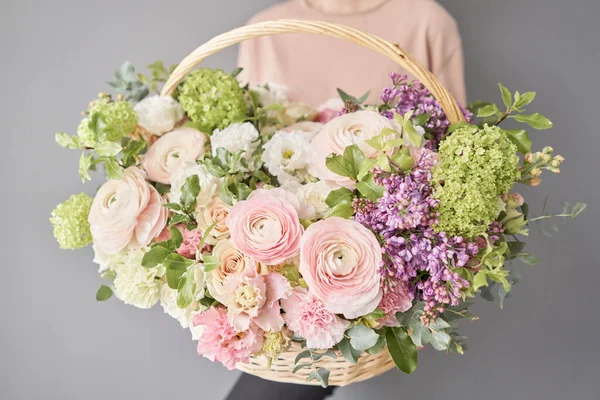 Virágok szállítása. Virágkötészet nagy fonott kosárban. Gyönyörű csokor vegyes virág női kézben. Virágüzlet koncepció. Jóképű friss csokor.. — Stock Fotó