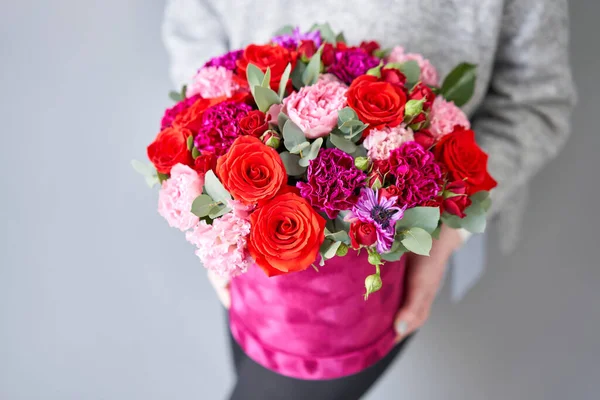Red and violet floral bunch in Velour round box. European floral shop. Bouquet of beautiful Mixed flowers in woman hand. — Stockfoto