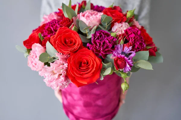 Bando floral vermelho e violeta na caixa redonda Velour. Loja floral europeia. Buquê de belas flores mistas na mão da mulher . — Fotografia de Stock