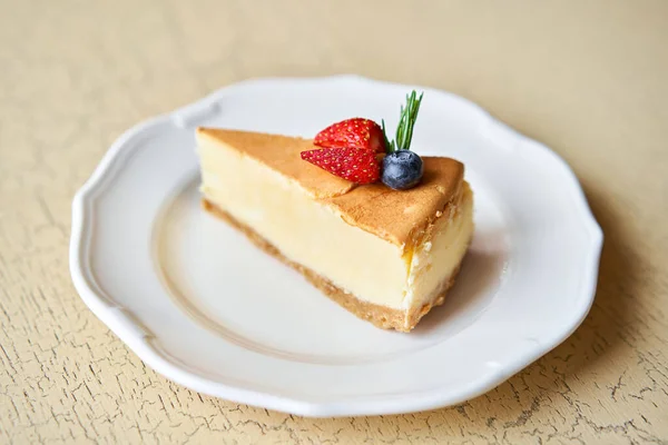 Closeup piece of delicious cheesecake with strawberry and mint leaves on white plate. — Stock Photo, Image