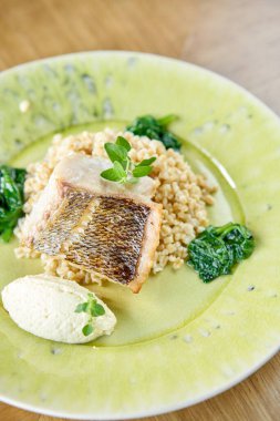 Kavrulmuş turna balığı ya da bulgur balıklı morina balığı. Ispanakla süslenmiş bir tabak. Restoran menüsü