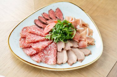 Et tabağı, lezzet ve Anantipasto. Salam, biftek, Parma jambonu, füme ördek göğsü. Restoran menüsü.