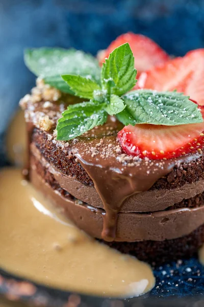 Closeup chocolate sponge cake, with caramel, decorated with strawberries and mint leaf. Breakfast in the cafe, morning coffee. on wooden table. Restaurant menu — Stock Photo, Image