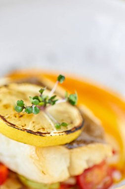 Kavrulmuş turna levrek veya pişmiş sebze ile morina balığı. Çanak limon bir dilim ile dekore edilmiştir. Restoran menüsü