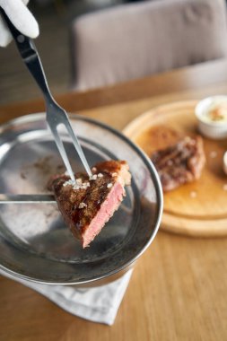 Garson elinde ızgara çizgili biftek, yanında lahana turşusu ve iki sos tutuyor. Striptiz bifteği, aynı zamanda New York bifteği. Tahta bir tahtanın üzerinde hizmet veriyor. Barbekü restoran menüsü.