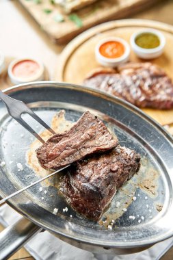 Garson bir bıçakla ızgara et kesiyor. Izgara biftek, lahana turşusu ve iki soslu barbekü restoranı menüsü..