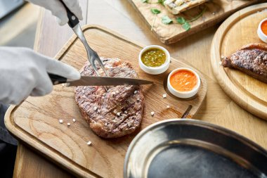 Garson tahta tahtada kaburga bifteği kesiyor. Barbekü restoran menüsü.