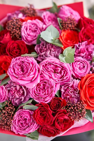 Closeup Bright berry color, Beautiful bouquet of mixed flowers in womans hands. the work of the florist at a flower shop. Delivery fresh cut flower. European floral shop. — Stock Photo, Image