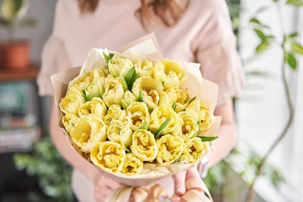 Желтый пастельного цвета тюльпаны в руке женщины. Молодая красивая женщина с весенним букетом. Куча свежих срезанных весенних цветов в женских руках — стоковое фото