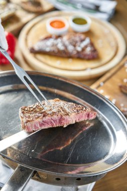 Garson elinde ızgara çizgili biftek, yanında lahana turşusu ve iki sos tutuyor. Striptiz bifteği, aynı zamanda New York bifteği. Tahta bir tahtanın üzerinde hizmet veriyor. Barbekü restoran menüsü.