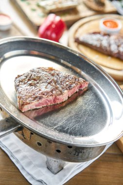 Izgara çizgili biftek. Ya biftek ya da kömürlü metal bir tabakta New York şeridi. Barbekü restoran menüsü.