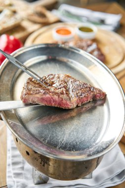 Garson elinde ızgara çizgili biftek, yanında lahana turşusu ve iki sos tutuyor. Striptiz bifteği, aynı zamanda New York bifteği. Tahta bir tahtanın üzerinde hizmet veriyor. Barbekü restoran menüsü.