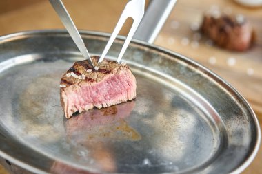 Garson bir bıçakla ızgara et kesiyor. Kızarmış sığır filetosu şatobriyan ve madalyon bifteği turşulu lahana ve iki sosla birlikte. Barbekü restoran menüsü.