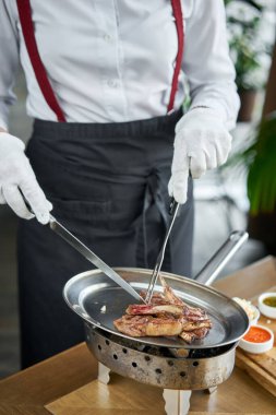 Garson bıçakla kasaplık yapıyor. Kuzu pirzolası, kemikli ızgara et. Barbekü lokantası menüsü, bir dizi farklı etin fotoğrafları.