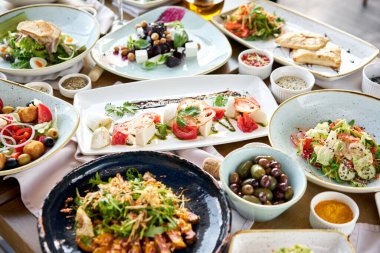 Masada bir sürü farklı lezzetli yemek var. Masada çeşitli abur cuburlar ve antipastalar var. Restoran menüsü. İtalyan mutfağı